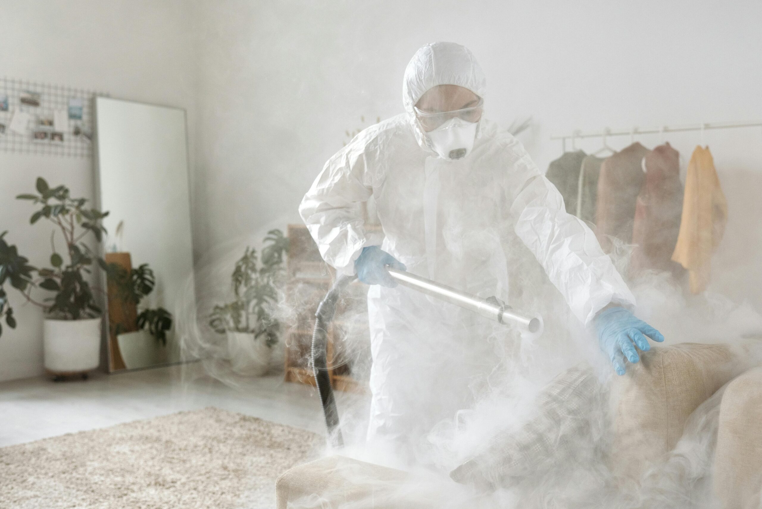 A person in protective suit disinfecting a room to eliminate viruses and bacteria.